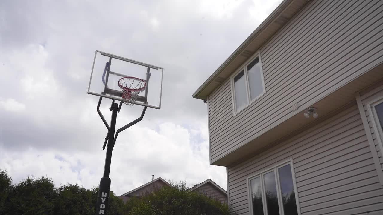 A timelapse of a backyard basketball hoop on a mildy cloudy sunny day