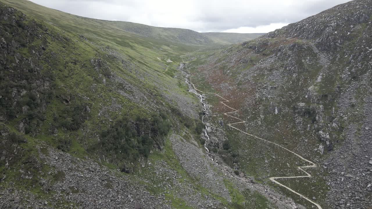 Sentiero escursionistico e ruscello lungo la valle di Glendalough nella contea di Wicklow, Irlanda - ripresa aerea con drone