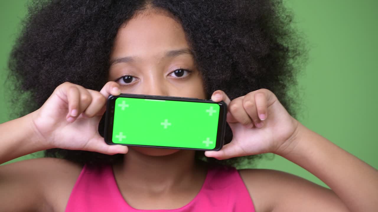 joven africana con cabello afro mostrando el teléfono