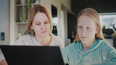 A-woman-with-her-daughter-use-a-laptop,-mom-helps-her-daughter-with-distance-learning