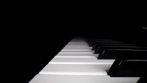 low profile wide angle macro of electronic keyboard - moving backwards aligned in the middle of the white keys, as the song assist lights the keys a red glow