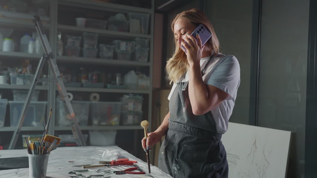 Artista donna che parla al telefono in uno studio d'arte.