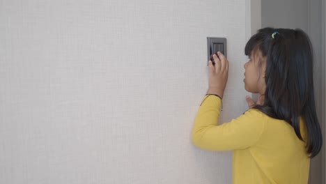 niña pequeña volviendo un interruptor de luz en una puerta