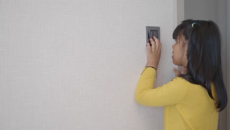 little girl flipping a light switch in a doorway