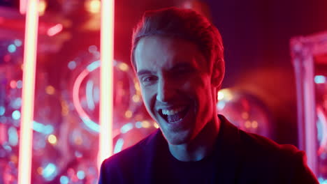 hombre alegre sonriendo en un club nocturno. persona masculina riendo en el fondo de luces de neón