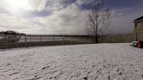 time lapse of a suburban backyard with a thin layer of snow melting as spring begins - tilt down time lapse