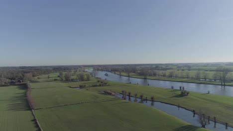 Wide-drone-shot-of-grass-fields-with-birds-and-water