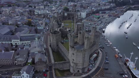 Alte-Caernarfon-Castle-Walisische-Hafenstadt-Luftbild-Mittelalterliches-Wahrzeichen-Am-Wasser-Mit-Blick-Auf-Die-Rechte-Orbit