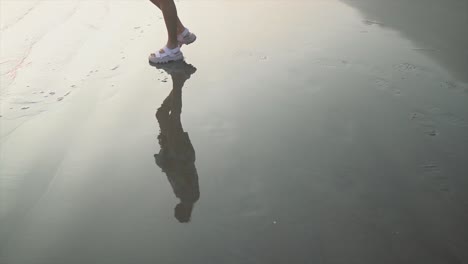 girl walking around on the wet sand in the beach with sandals