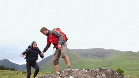 Hiking-couple-reaching-the-summit-and-looking-around-them