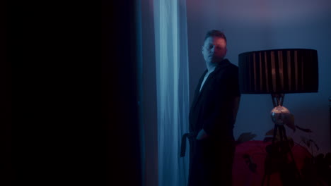 man in a robe by the window at night