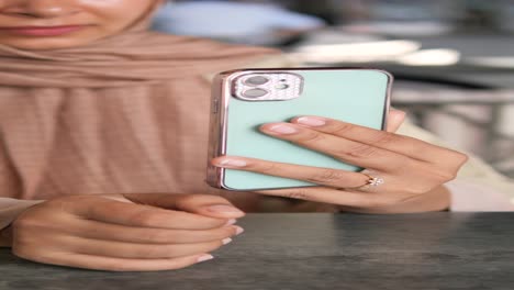 woman in hijab using a mint green smartphone