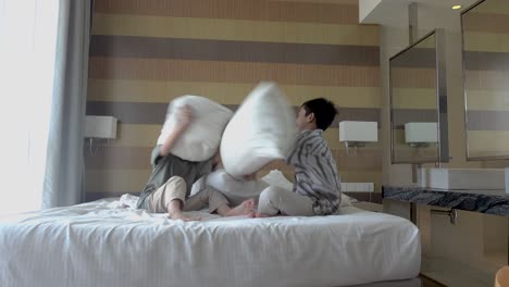 two boys having a pillow fight in a hotel room
