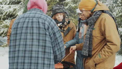 friends cooking bbq at campsite in winter forest