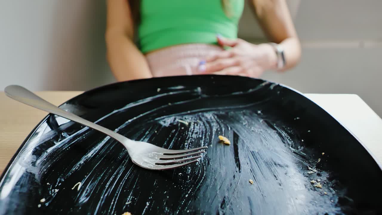 Slow motion shot zooming in on dirty plate with woman in discomfort