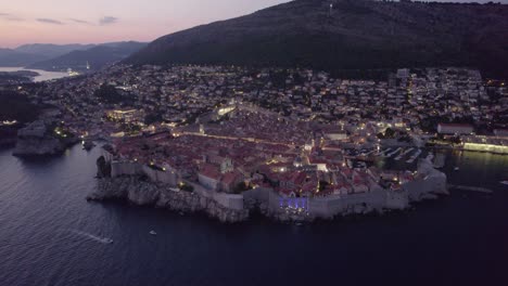 illuminated streets of dubrovnik old town at twilight, aerial over adriatic