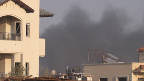 black smoke can be seen rising between buildings destroyed by israeli missile attacks in the gaza strip