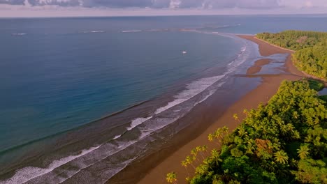aerial view of uvita, costa rica's wide tropical beach and ocean, featuring clear waters and lush palm forests, all bathed in the gentle light of sunrise