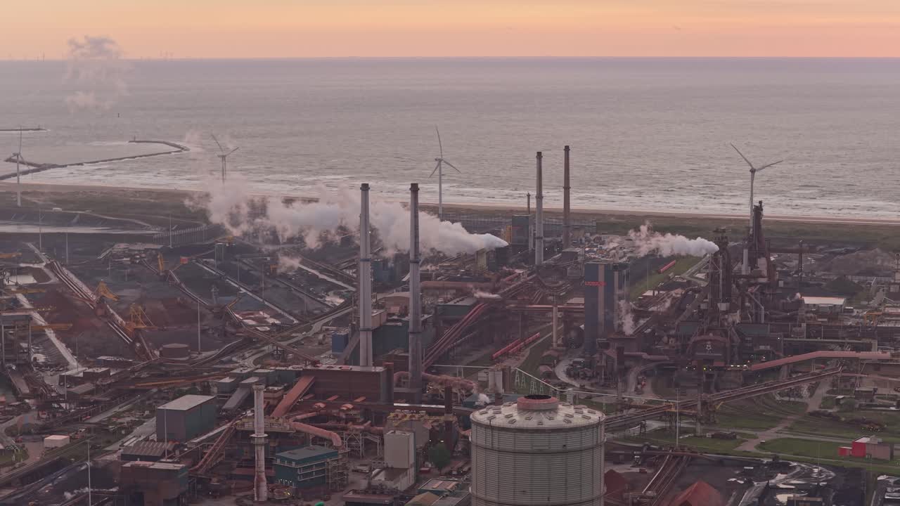 Wide aerial of factory chimneys smoking on bright sunny evening sky