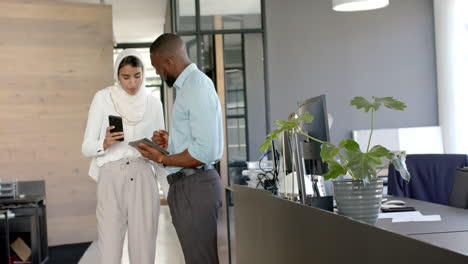 discussing work, colleagues using smartphone and tablet in modern office setting