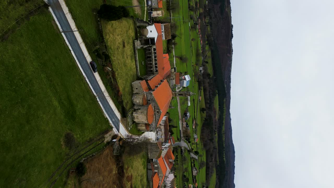 Rear pullback aerial from Santa Maria de Xunqueira monastery on cloudy day
