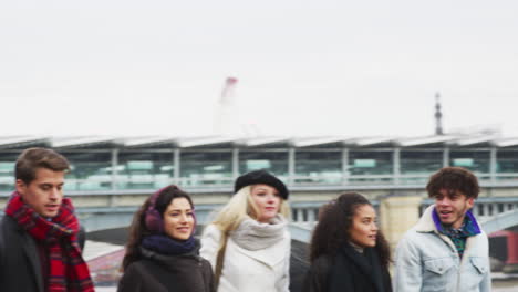 friends walking along south bank on winter visit to london