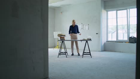 architect working on blueprints in an unfinished room.