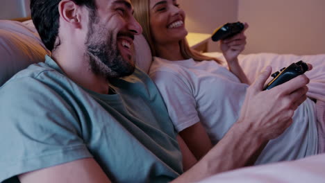 couple playing video games in bed