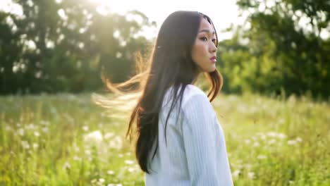 a young woman with long hair stands in a vibrant green field, exuding grace and serenity as she walks with purpose under a bright sunlit sky