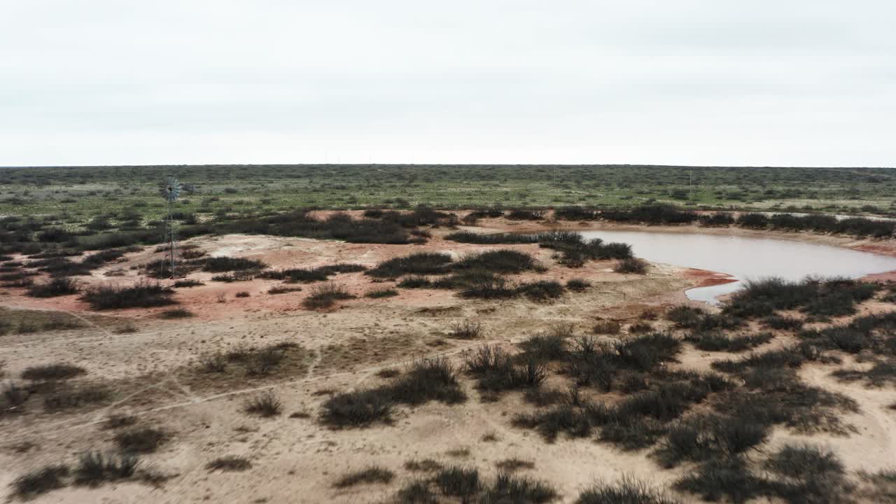 Veduta a distanza di un vecchio mulino a vento e di una vasta pianura deserta.