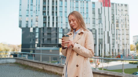 happy mature business woman enjoying morning coffee hot drink and smiling on downtown city street