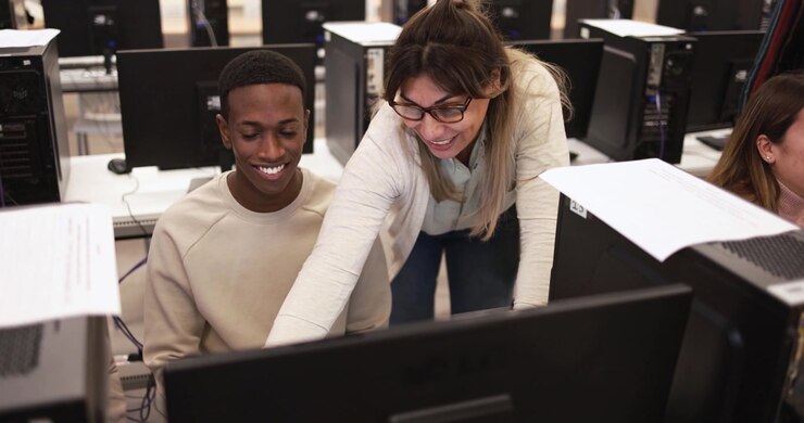 Teacher Assisting Student with Computer Work in Classroom