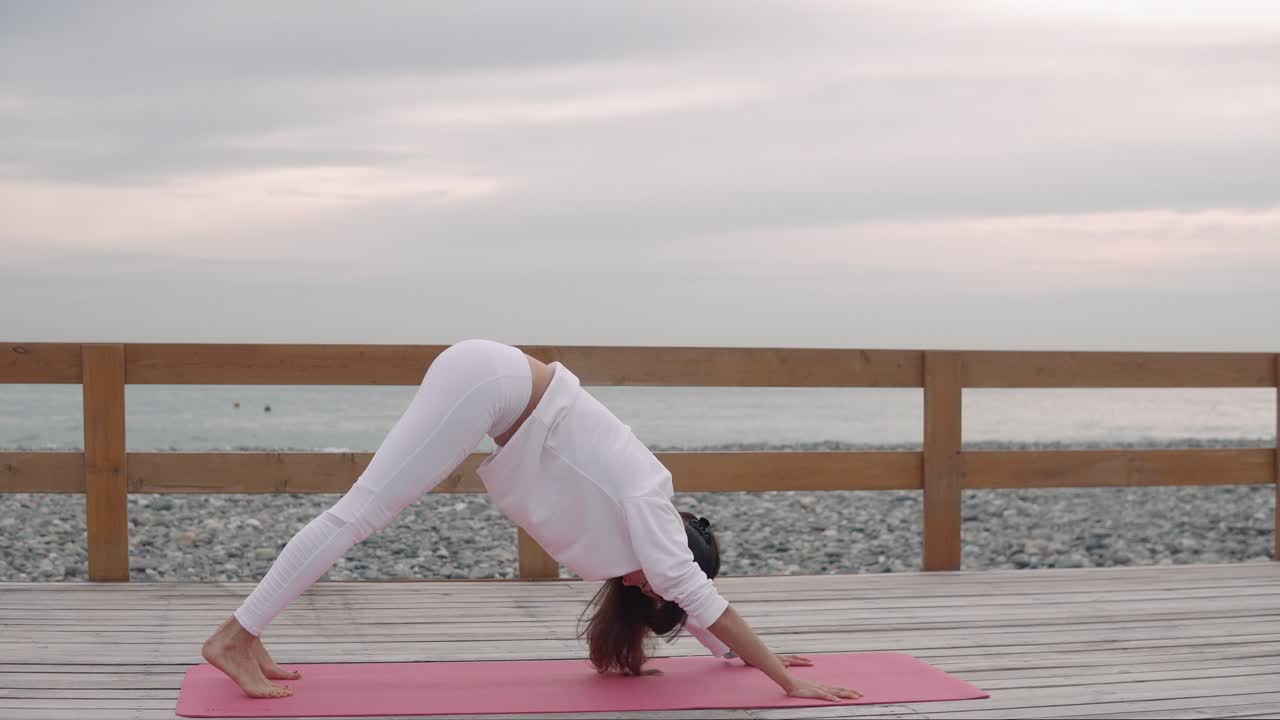 mujer practicando yoga posa en un paseo marítimo de la playa