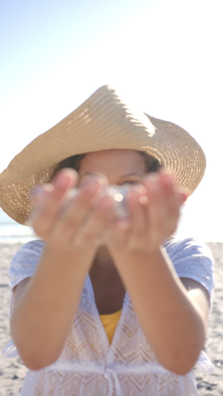 Video verticale: Donna che tiene la sabbia con entrambe le mani, godendosi una giornata di sole in spiaggia