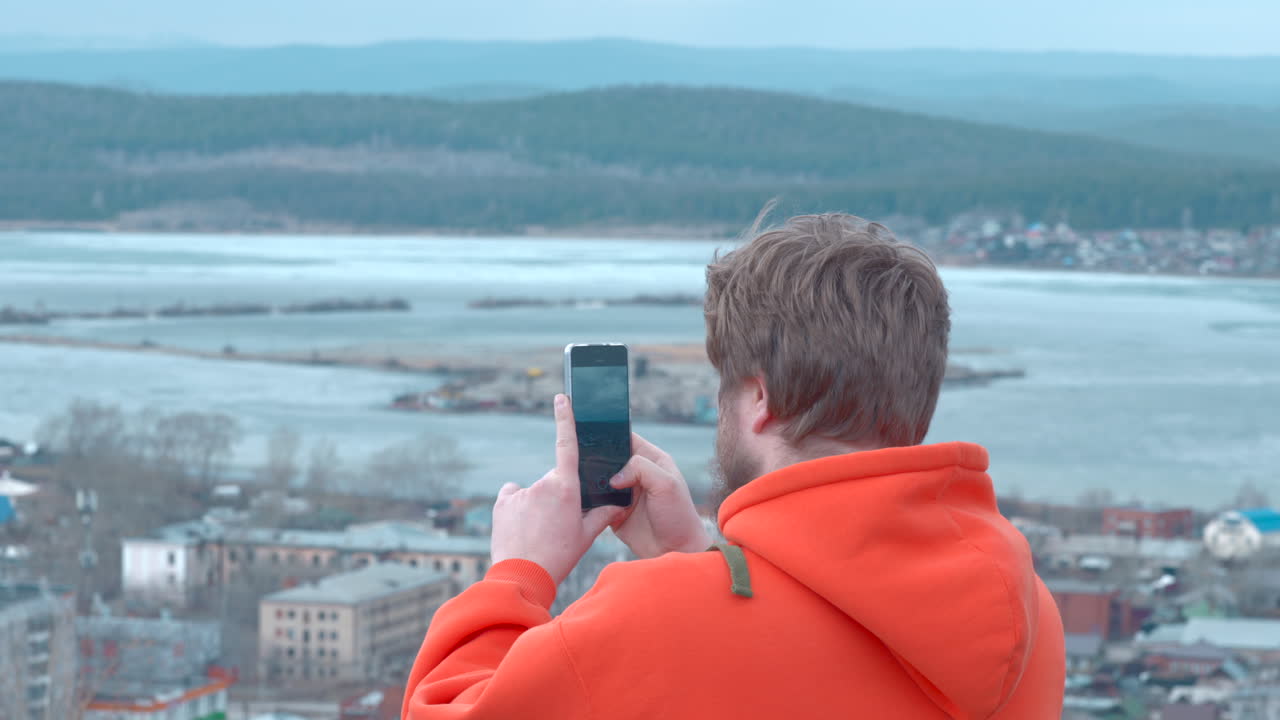 Uomo che scatta una foto del paesaggio cittadino con lo smartphone