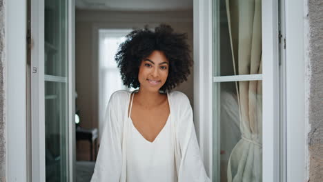 African-model-looking-window-at-home-portrait.-Positive-woman-catching-raindrops