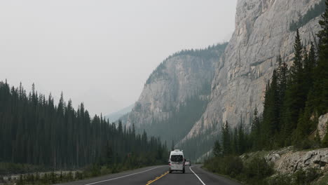 Wide-Angle-Moving-Forward-Down-a-Road-Through-Tall-Mountains-in-4K