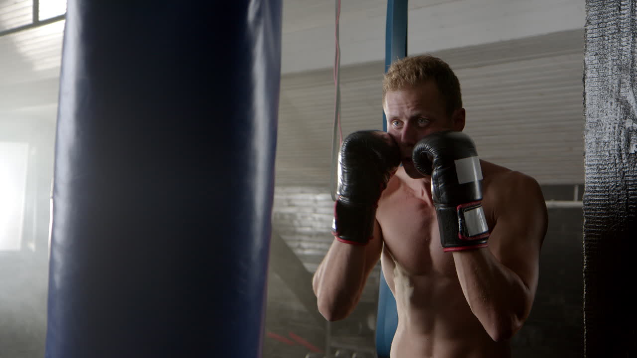 Boxer training with punching bag in the gym