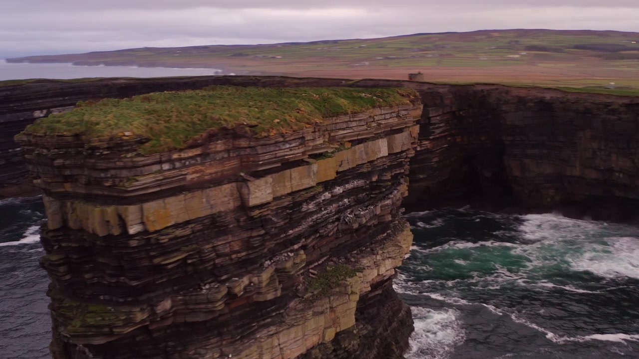 Aerial orbit right off coast of Downpatrick Head cliffs, showing the Dun Briste sea stack surrounded by waves