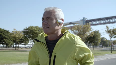 active old jogger with headphones running outside