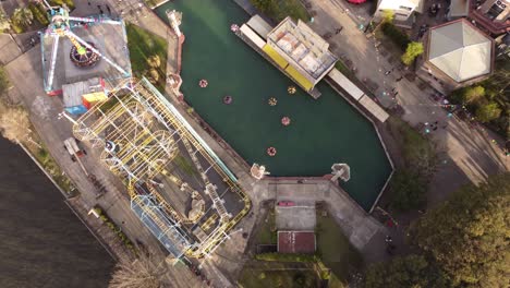 una toma aérea orbital dinámica de la montaña rusa, el frisbee y el paseo en bote parachoques en acción en el parque de diversiones parque de la costa en tigre, buenos aires