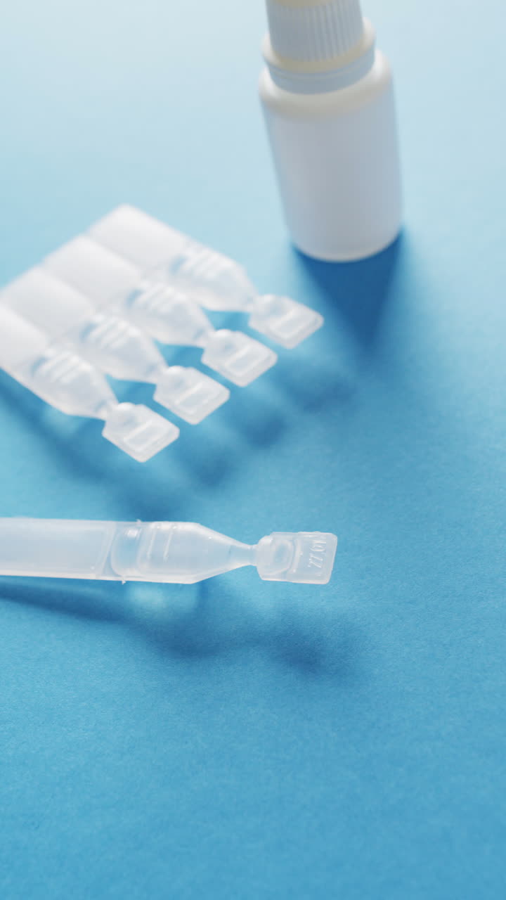 Vertical video of medical drops and test tubes on blue background