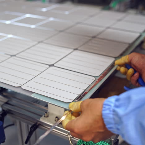 worker's hands measuring solar panel. factory for producing solar cells indoors. close-up.
