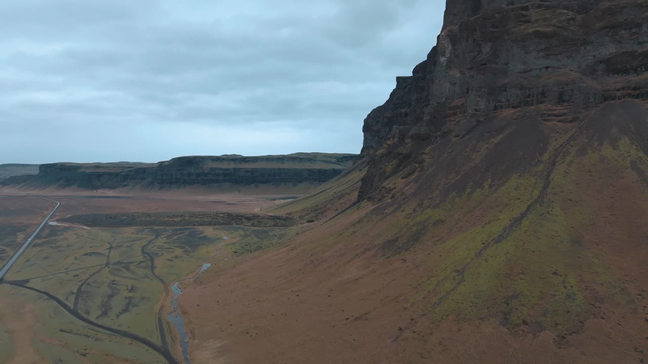 vuelo a lo largo de una montaña islandesa en un día lluvioso por encima de la carretera de circunvalación - hacia adelante, a gran altitud aérea