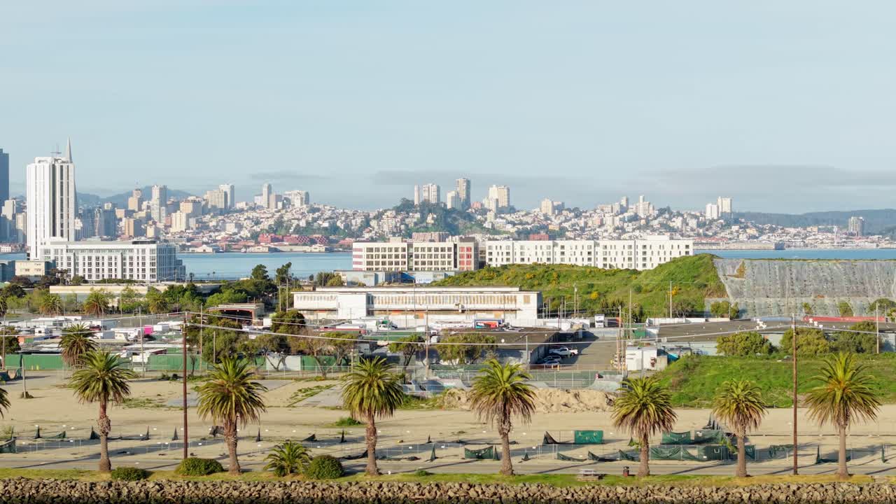 A detailed right to left aerial view of the town of Treasure Island with the San Francisco cityscape in the background. Filmed in real time in 4K after sunrise.