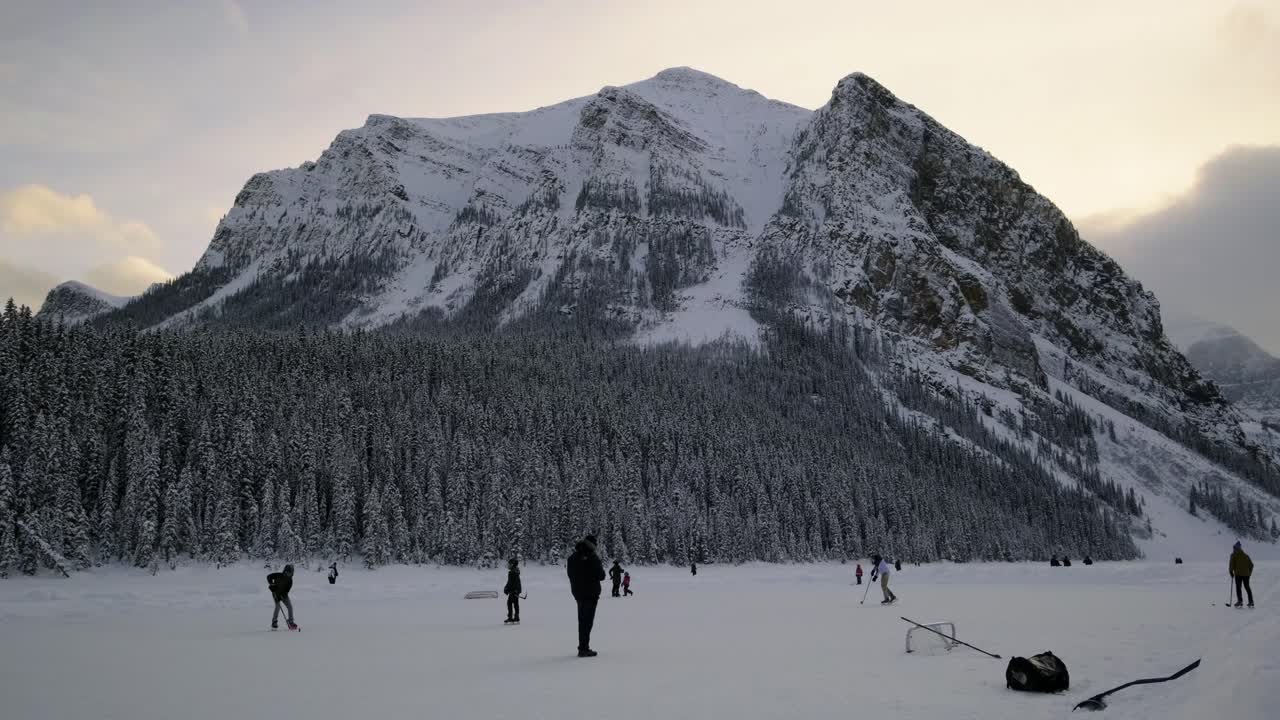Tourists Playing Ice Hockey On The Alpine Lake Louise in Banff National Park Located In Alberta, Canada. wide shot