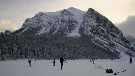 tourists playing ice hockey on the alpine lake louise in banff national park located in alberta, canada. wide shot