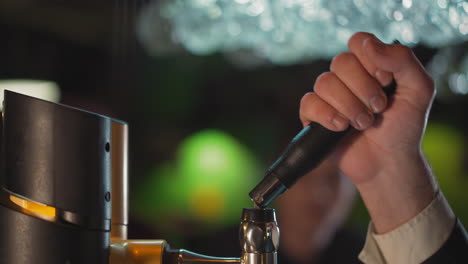 Barman-turns-beer-pump-lever-to-pour-drink-in-pub-closeup