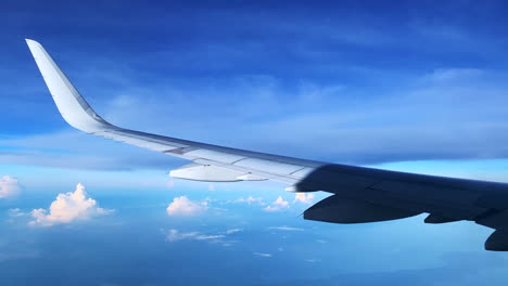 Footage-of-a-flying-Airplane-into-the-blue-cloudy-sky-showing-the-left-wing