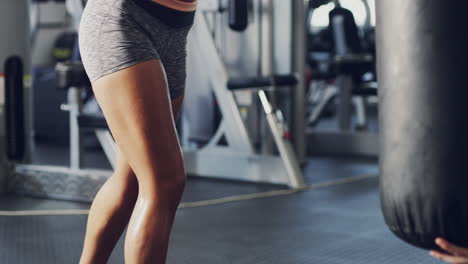 mujer trabajando en el gimnasio con bolsa de boxeo